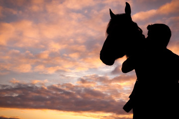 Silhouetted man and horse at sunset