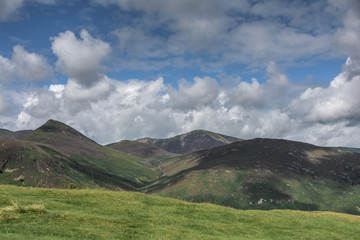 dramatic landscape with mountains, hills, lake and clouds formations