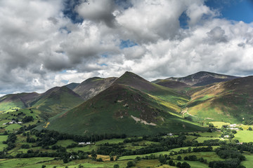 dramatic landscape with mountains, hills, lake and clouds formations