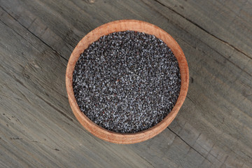poppy seeds in wooden bowl on wooden background with copy space. top view