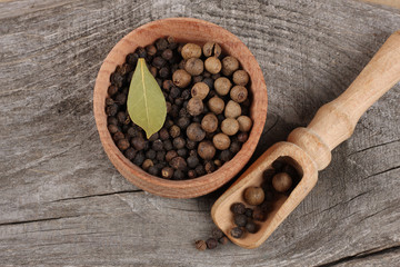 black pepper. peppercorns in wooden bowl on wooden background with copy space. top view