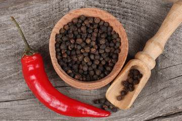 black pepper. peppercorns in wooden bowl on wooden background with copy space. top view
