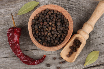 black pepper. peppercorns in wooden bowl on wooden background with copy space. top view