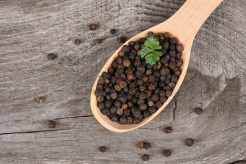 black pepper. peppercorns in wooden spoon on wooden background with copy space. top view