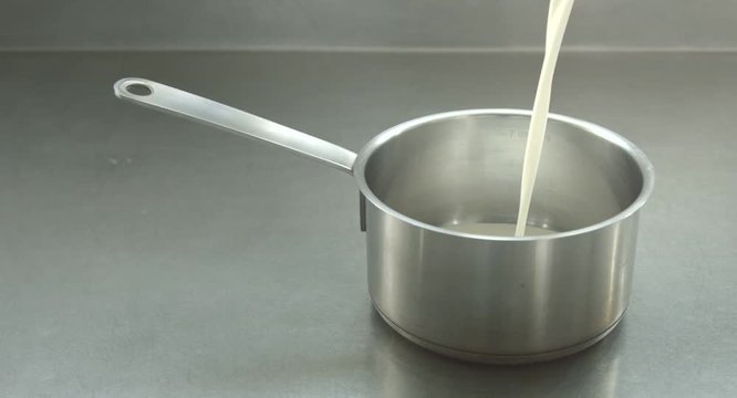 close up milk pour from jar on pot