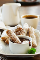 Churros with hot chocolate and powdered sugar.