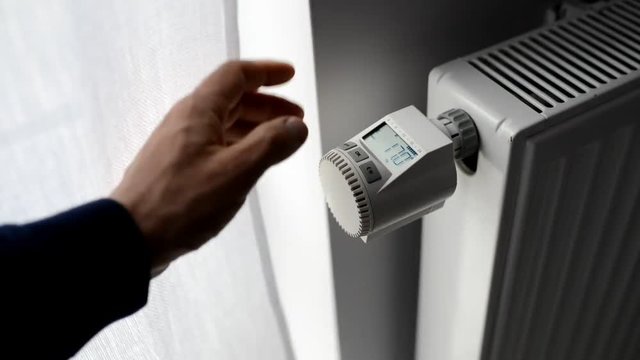 Close up on male hand adjusting temperature on heater valve