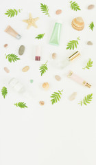 Cosmetics background. Cosmetics SPA makeup tubes, bottles, sea pebbles and shells on white background. Flat lay, top view.