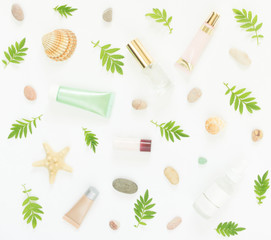 Cosmetics background. Cosmetics SPA makeup tubes, bottles, sea pebbles and shells on white background. Flat lay, top view.