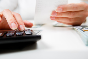savings, finances, economy and home concept - close up of hands with calculator counting money and making notes at home