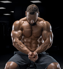 Fototapeta na wymiar Adult guy bodybuilder posing in gym