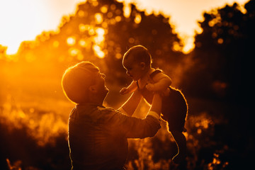 Woman raises little girl up in the lights of sunset