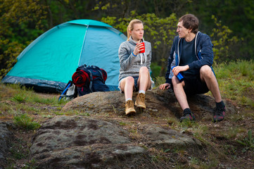 couple of hikers with backpacks and hot tea at early morning. Travel, vacation, holidays and adventure concept. Forest Mountain landscape background