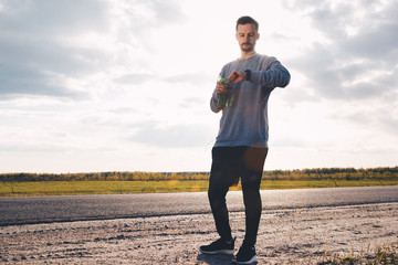 Athlete with smart watch In a relaxed pose. Sunset on the background. The runner prepares to run. Runner counts calories