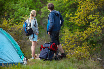 Man and woman tourists backpackers looking for way on trip while resting. Young couple hikers searching looking for direction guide. Backpacking summer vacation travel.