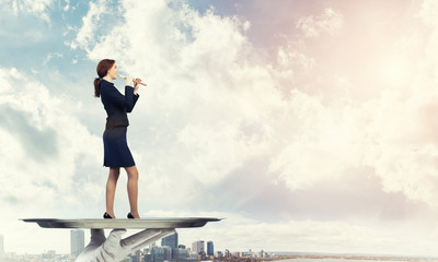 Obraz premium Attractive businesswoman on metal tray playing fife against cityscape background