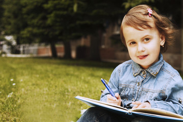Little beautiful girl writing in her book (Education, knowledge, work, success concept)