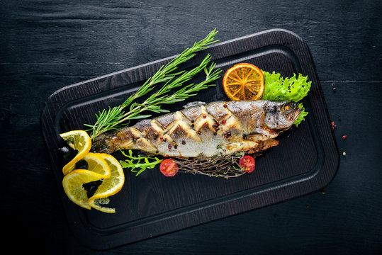 Trout fish baked with aromatic herbs and spices. On Wooden background.