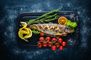 Trout fish baked with aromatic herbs and spices. On Wooden background.