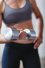 Fototapeta na wymiar Young athletic woman training hard with dumbells at home. Fitness and healthy lifestyle concept with beautiful sportive caucasian model