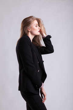Styled blonde in fashion suit on gray background in studio photo. Elegant blonde