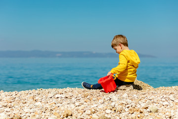 cute baby boy playing on the beach with water