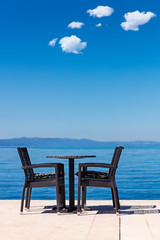 background of two chairs and beach and small bag and table place