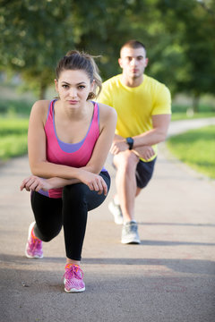 Couple stretching before jogging at the bench in the park