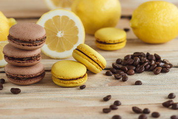 Yellow and brown french macarons with lemons and coffee beans on the wooden board