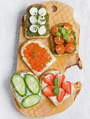 Healthy snack, healthy Breakfast, Bruschetta with pesto, mozzarella, red caviar and vegetables. Cottage cheese and strawberries.