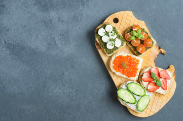 Healthy snack, healthy Breakfast, Bruschetta with pesto, mozzarella, red caviar and vegetables. Cottage cheese and strawberries.