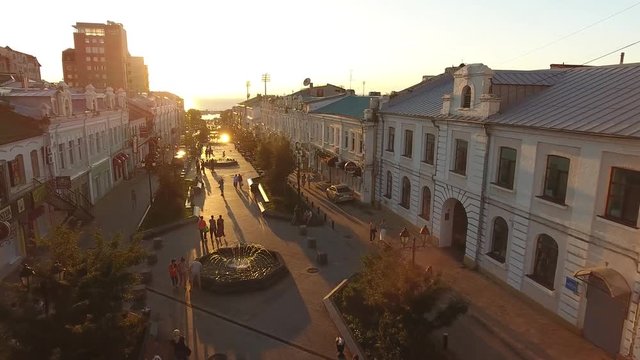 Old small brick houses walking street. Vladivostok Russia Millionka district. Beautiful summer evening sunset. Long shadows. Rooftops mansards. Aerial drone 4k flight to the sun People walk pedestrian