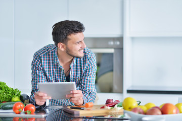 Happy man using digital tablet in kitchen at home