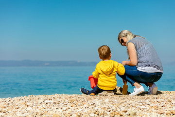 A happy mother and young child boy son having fun on a sunny beach