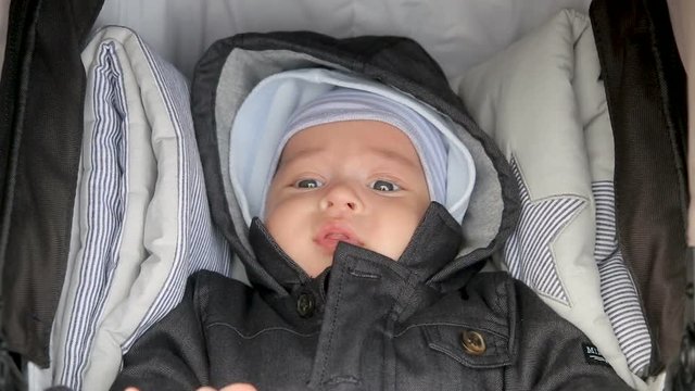 infant lies in a sidecar in a hat and hood in the spring