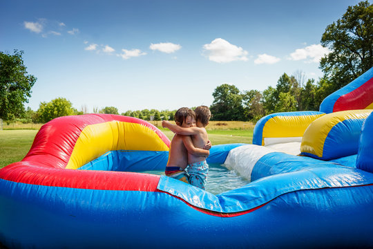 Two boys hugging on an inflatable water slide
