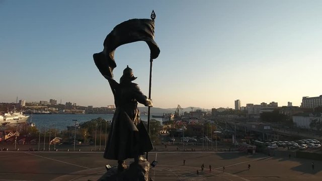 Central square Fighters for Soviet Power in the Far East monument. Vladivostok Russia. Main streets. City panorama people walk. Cinematic Aerial drone flight around contast sunset 4k