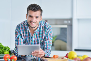 Happy man using digital tablet in kitchen at home