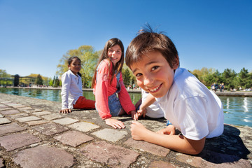 Cute boy sitting on the embankment with friends