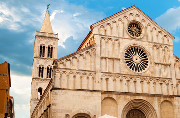 Fototapeta premium Architectural details of Saint Anastasia Cathedral and tower made of white stone on a summer morning. Dramatic cloudy sky. Zadar center, Croatia