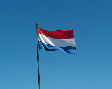 Flag of the Netherlands waving in wind, blue sky