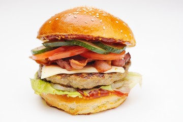 Appetizing burger with chop, bacon, bacon, cucumber, greens, salad on white background