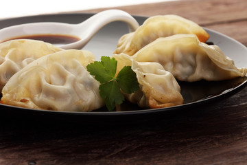 A plate of Japanese gyoza dumplings sitting on a rustic wooden table.