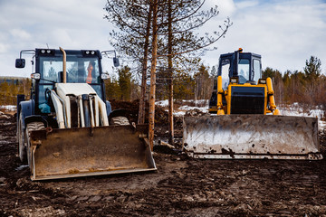 Tractor loader and bulldozer on a caterpillar drive is parked in the mud. Concept road construction. © Parilov