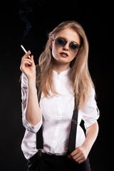 Obraz premium Blonde woman smoking on black background in studio photo