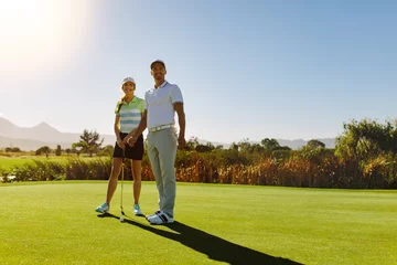 Papier Peint photo Lavable Golf Male and female golfers at field on sunny day
