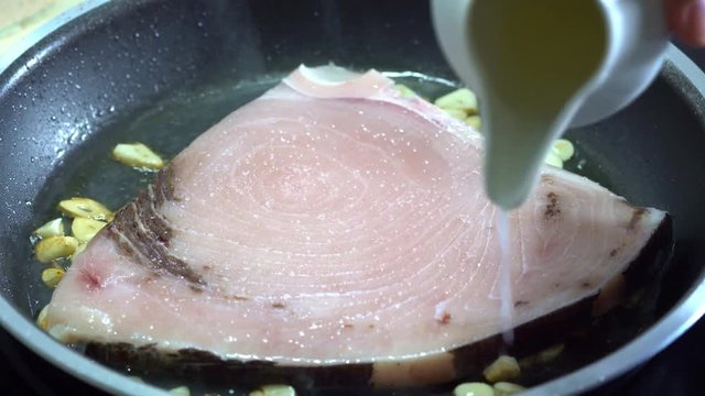 Add lemon juice to the swordfish in the pan.