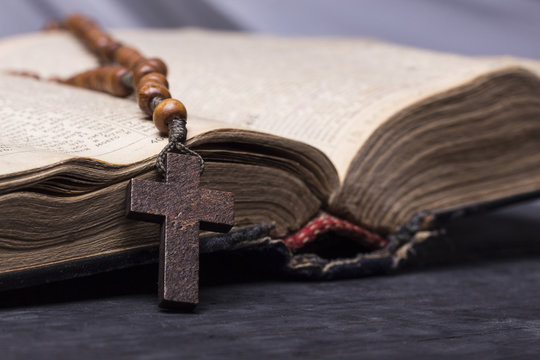 Rosary and  cross  on the Bible on a wooden background. Holy book.
