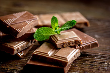 chopped chocolate pieces with mint for dessert wooden desk background