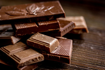 black and milk chocolate pieces wooden table background